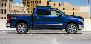 blue ram truck in a parking lot with tall buildings behind it